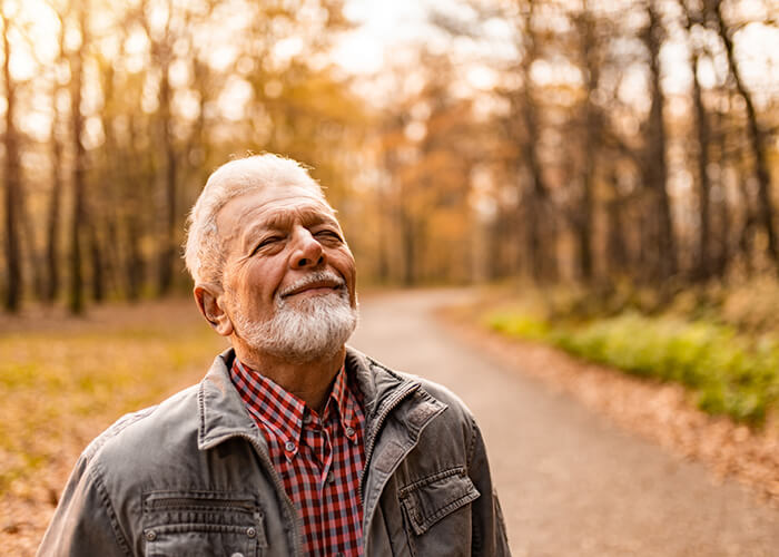 Image of an elderly man walking on a trail and breathing